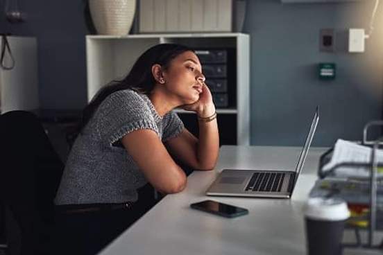 woman staring into the distance at her desk