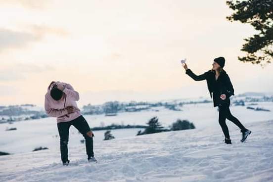 woman throwing snowball at man