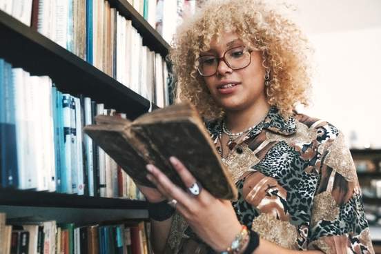 young woman reading old book in library