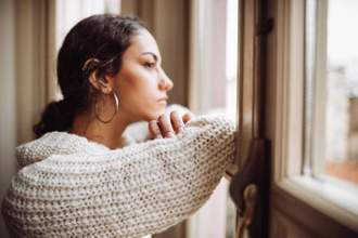 woman wistfully looking out of the front window
