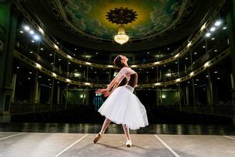 A female ballerina rehearsing on the theater stage