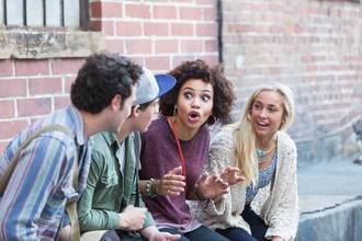 A group of friends sitting together listening to a woman tell an over the top story