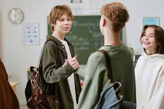 Two teenagers greeting in the classroom before school