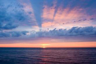 a beautiful pink and blue sunset over a large body of water
