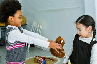 a child giving a teddy bear to their friend