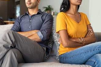 a couple looking upset with their arms crossed sitting turned away from each other