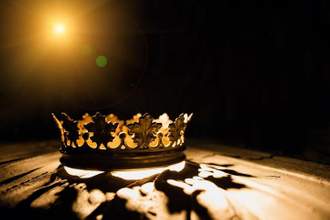 a crown on a black background is illuminated by a bright light