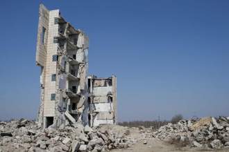a dilapidated building that has half fallen littered with rubble all around the base