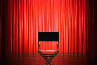 a directors chair sitting on the stage with a red curtain in the background
