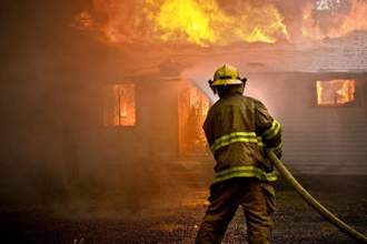 a firefighter spraying water on a house fire