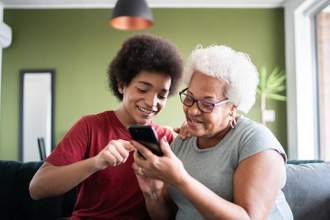 a grandchild teaching his grandma how to use her new phone