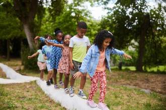 a group of children balancing on a platform walking in a line