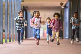 a group of children running out of school at the end of their day