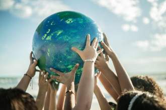 a group of kids hands holding up the globe at the beach