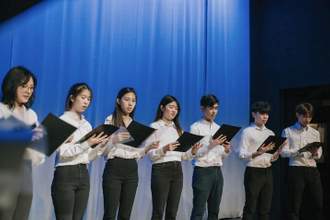 a group of teens singing on stage as a choir