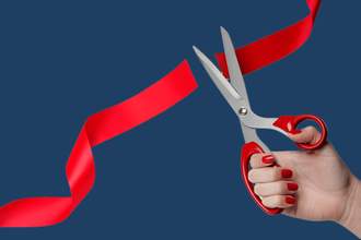 a hand cutting a red ribbon