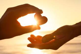 a hand passing over a heart to someone