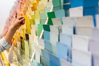 a hand reaching for a color swatch on a wall