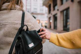 a hand sneakily taking a phone out of someones backpack