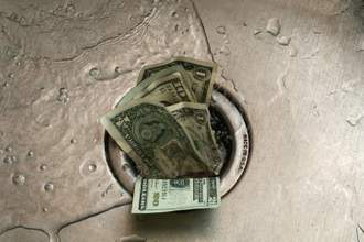 a handful of cash being washed down the sink drain