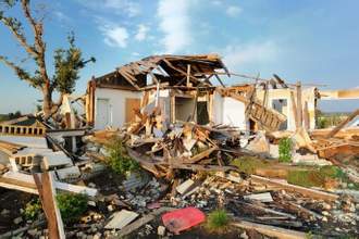 a home that has been absolutely demolished by some sort of store with its contents all over the foreground of the image