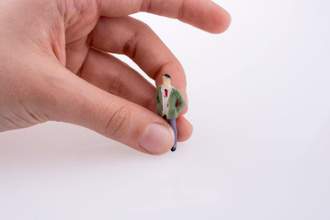 a human hand holding a tiny figure of a business man