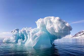 a large glacier that has a unique cloud-like form with icicles falling down in the middle of the ocean