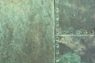 a large sheet of metal with bolts that has become a tinted green