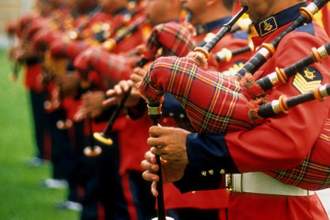 a lineup of men standing and playing the bagpipes together