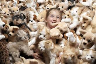 a little girl looking super happy while surrounded by hundreds of dog stuffed animals
