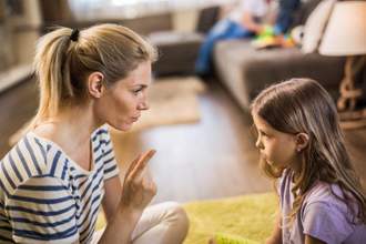 a mother sitting at her daughters level while scolding her