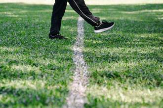 a pair of legs stepping over a line in grass
