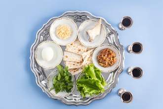 a pesach plate with traditional symbols of the jewish passover and four glasses of red kosher wine