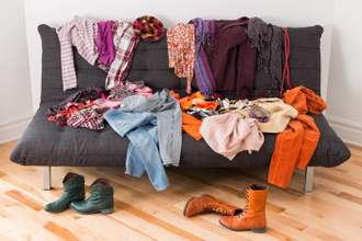 a pile of clothes and shoes laying all over a couch