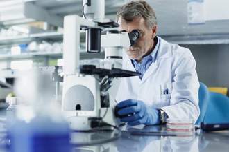 a scientist in a lab looking into his microscope