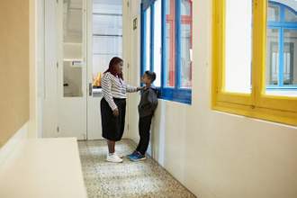 a teacher with her hand on a students shoulder speaking to him earnestly in the school hallway