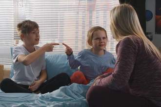 a woman speaking to her children while they point in accusation to eachother passing the blame