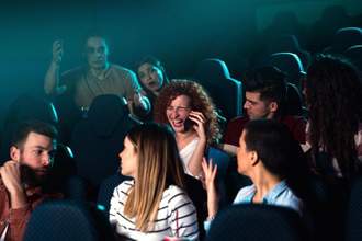 a woman talking on the phone while everyone is trying to watch a movie