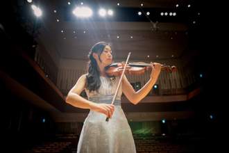 a young woman playing the violin in a concert hall