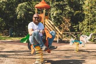 adult male having fun while riding horse spring rider at the childrens playground