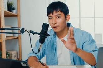 adult man talking into a microphone creating a podcast