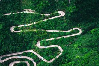 aerial view of a long winding road on a green mountainside