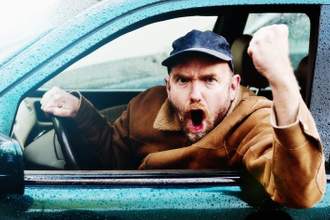 an adult male shaking his fist and yelling at the screen as he drives his car