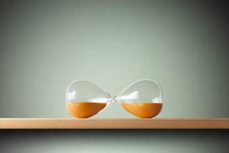 an hourglass tilted on its side so that the sand sits evenly in both glass bulbs