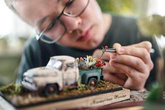 an individual working on adding details to a miniature model flower truck