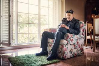 an older man sitting in his living room wearing his old biker outfit