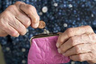 an older person taking a penny out of their coin purse