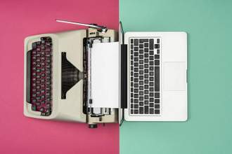 analog typewriter and digital laptop computer facing away from one another