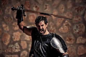 angry medieval solider brandishing a sword above his head