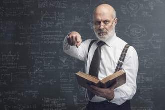 angry old professor standing in front of a cluttered chalkboard holding a book and pointing at the camera